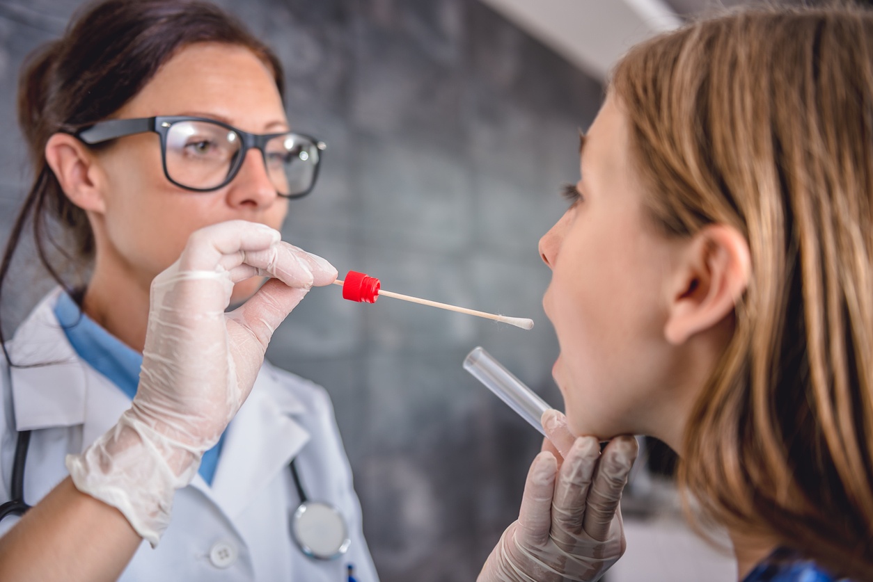 Female pediatrician using a swab to take a sample from a patient's throat
