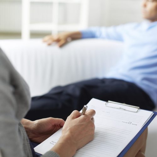 Female psychologist making notes during psychological therapy session